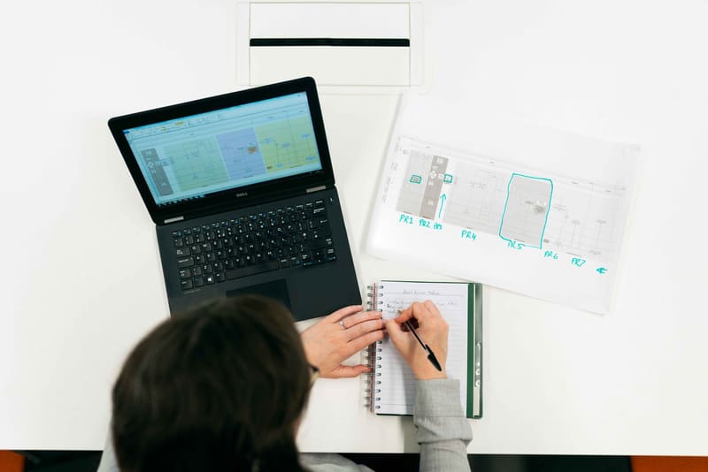 Kalkulation am Laptop neben einem Grundriss