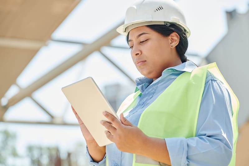 Bauleiterin prüft auf der Baustelle Angaben am Tablet