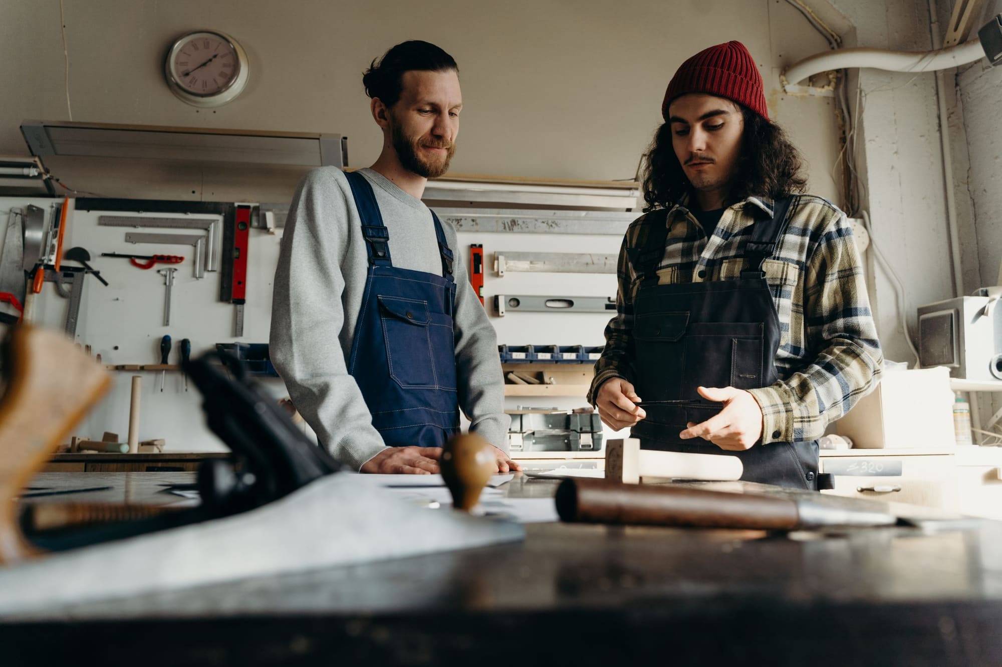 Zwei Handwerker besprechen ein Werkstück an der Werkbank