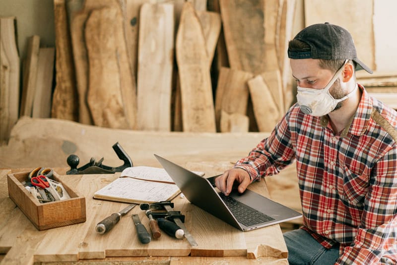Handwerker prüft Lumio-Vorschläge am Laptop in seiner Werkstatt